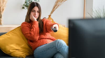 bored young woman watching tv in living room